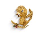 une image représentant une broche en forme d'oiseau en or, ornée de pierres colorées
