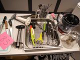 a sink filled with various kitchen utensils on a table