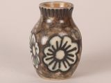 a brown vase with black and white flowers on it