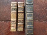 two old books sitting on top of a wooden table next to each other
