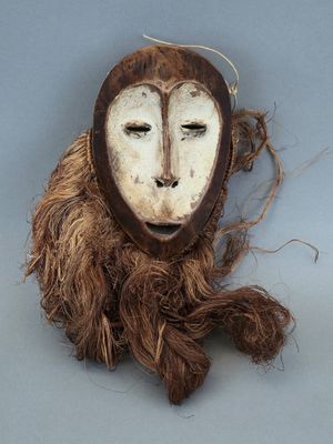 un masque marron et blanc accroché à un mur gris