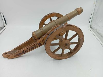 un petit canon en bois exposé dans une vitrine