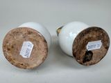 two white vases with labels on them sitting on a table