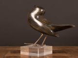 statue of a bird on a marble base on a wooden table