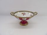 a red and white bowl on a gold stand
