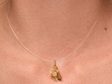 a close up of a woman wearing a gold necklace with a heart on it