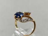 a close up of a gold ring with a blue sapphire and diamonds