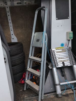 une échelle appuyée contre un mur, à côté d'une autre échelle