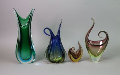 trois vases en verre de couleurs différentes posés l'un à côté de l'autre sur une surface blanche