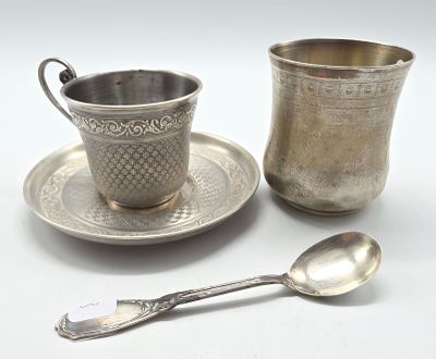 une tasse et une soucoupe en argent, avec une cuillère à côté