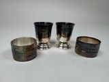 three silver cups with designs on them sitting on a white surface