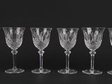 six wine glasses lined up in a row against a black background