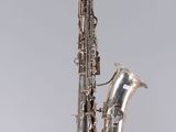 un vieux saxophone argenté posé sur une surface blanche