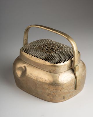 an old brass teapot with a handle on a white surface