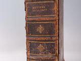 an old book sitting on top of a white table next to a white wall