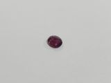 a red oval shaped ruby stone on a white surface