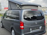 a grey van with a tent on top parked in a parking lot