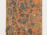 un livre aux motifs marbrés orange et noir posé sur une surface blanche