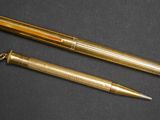 deux stylos dorés posés l'un à côté de l'autre sur une surface noire