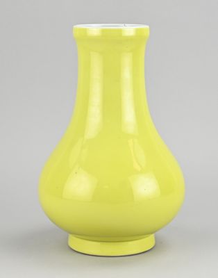yellow vase sitting on a gray surface with a gray background