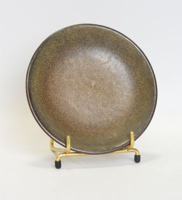 a brown plate on a gold stand on a white surface