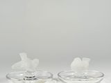 two clear glass candlesticks with birds on them on a white surface