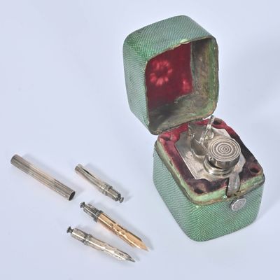 a green box with a silver object inside and a pen in it