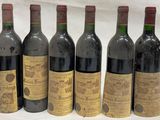 six bouteilles de vin sont alignées sur une table