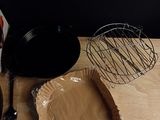 a wooden cutting board with a paper plate and a whisk on it