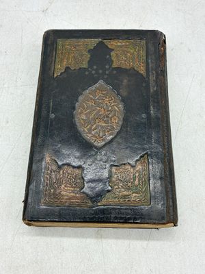 un livre noir à la couverture dorée sur un fond blanc