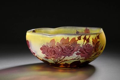 un bol jaune orné de fleurs rouges posé sur une table