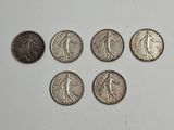 six types différents de pièces d'argent sur une surface blanche