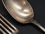 a silver spoon and a fork on a black table