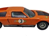 an orange toy car that is sitting on a white surface