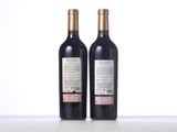 two bottles of red wine sitting on top of a white table
