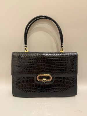 un sac à main en cuir de crocodile noir avec des finitions dorées