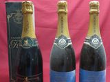 trois bouteilles de champagne et une boîte de vin sur fond rose