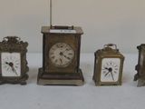 cinq horloges de tailles différentes posées sur une surface blanche
