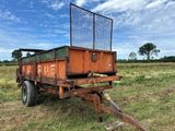une remorque orange rouillée, garée au milieu d'un champ