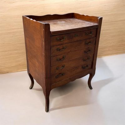 une petite commode en bois posée sur un sol blanc