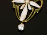 a close up of a brooch with a flower and a pearl