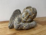 une petite statue représentant un ange assis sur une table en bois