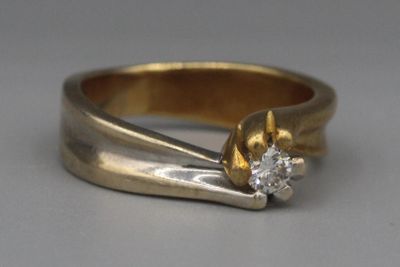 une bague en or sertie d'un diamant, posée sur une table
