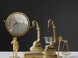 une table sur laquelle se trouvent une horloge, une balance et d'autres objets