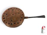 an old copper frying pan with a handle and holes in it