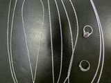 a lot of silver necklaces and rings on a black surface