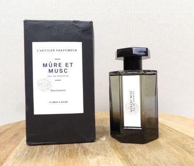 une photo d'un flacon de parfum posé sur une table en bois