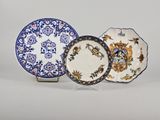 trois assiettes sont posées sur un support, sur une surface blanche