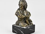 a bronze statue of a man sitting on a marble block