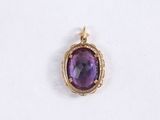 a close up of a pendant with a purple stone in it